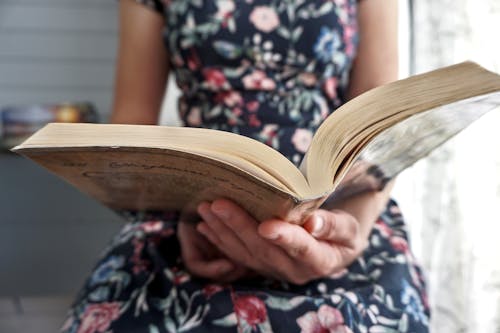 Free Person in Black and White Floral Dress Reading Book Stock Photo