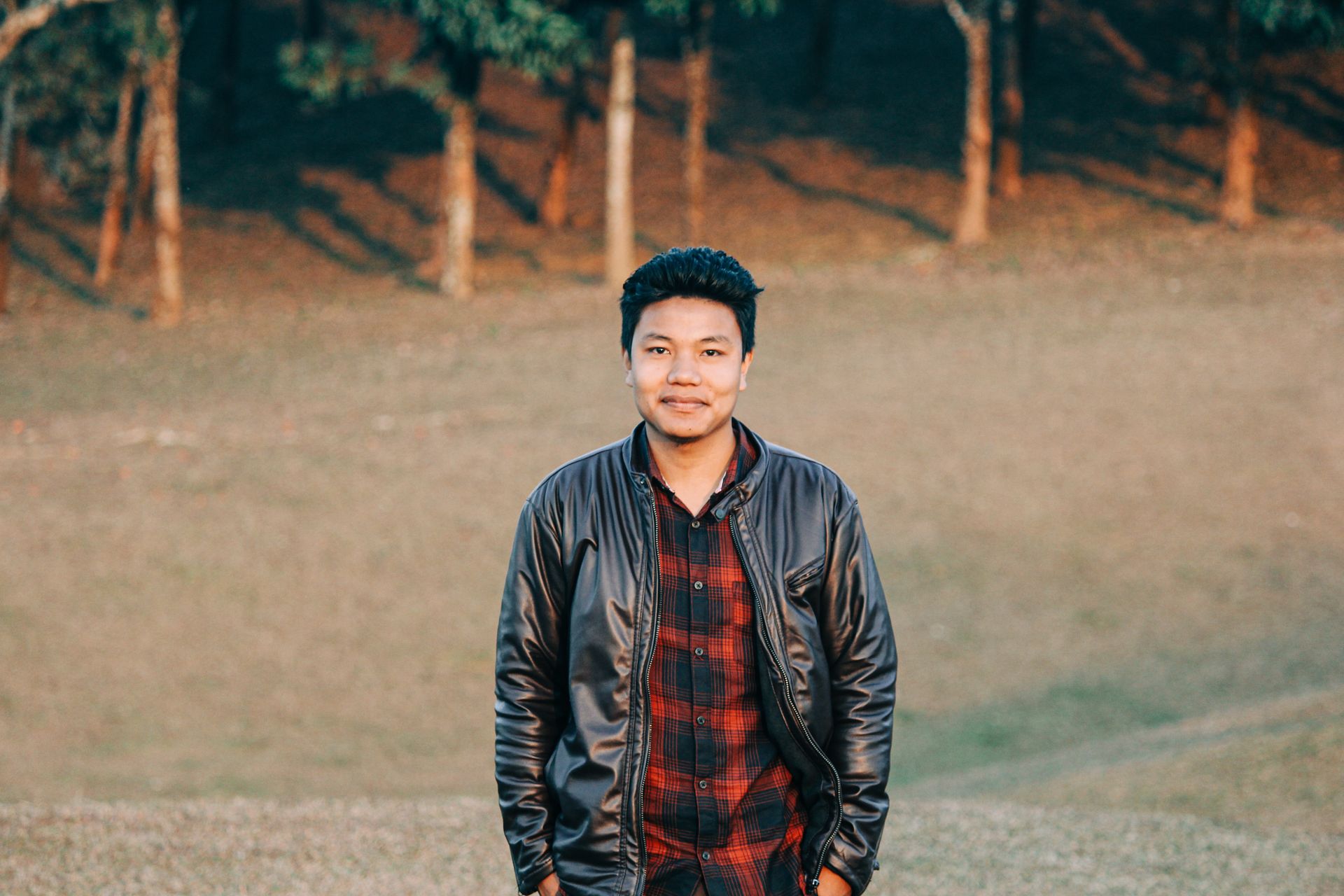 Casual portrait of a smiling man in a black leather jacket outdoors.