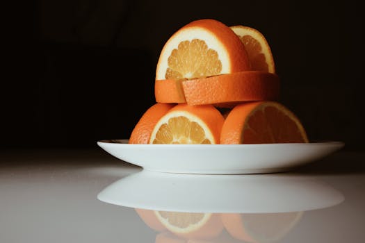 Stacked sliced oranges on a white plate with reflection, conveying freshness.