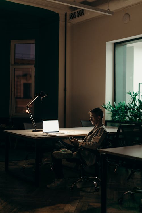 Man in Black Jacket Sitting on Chair in Front of Macbook