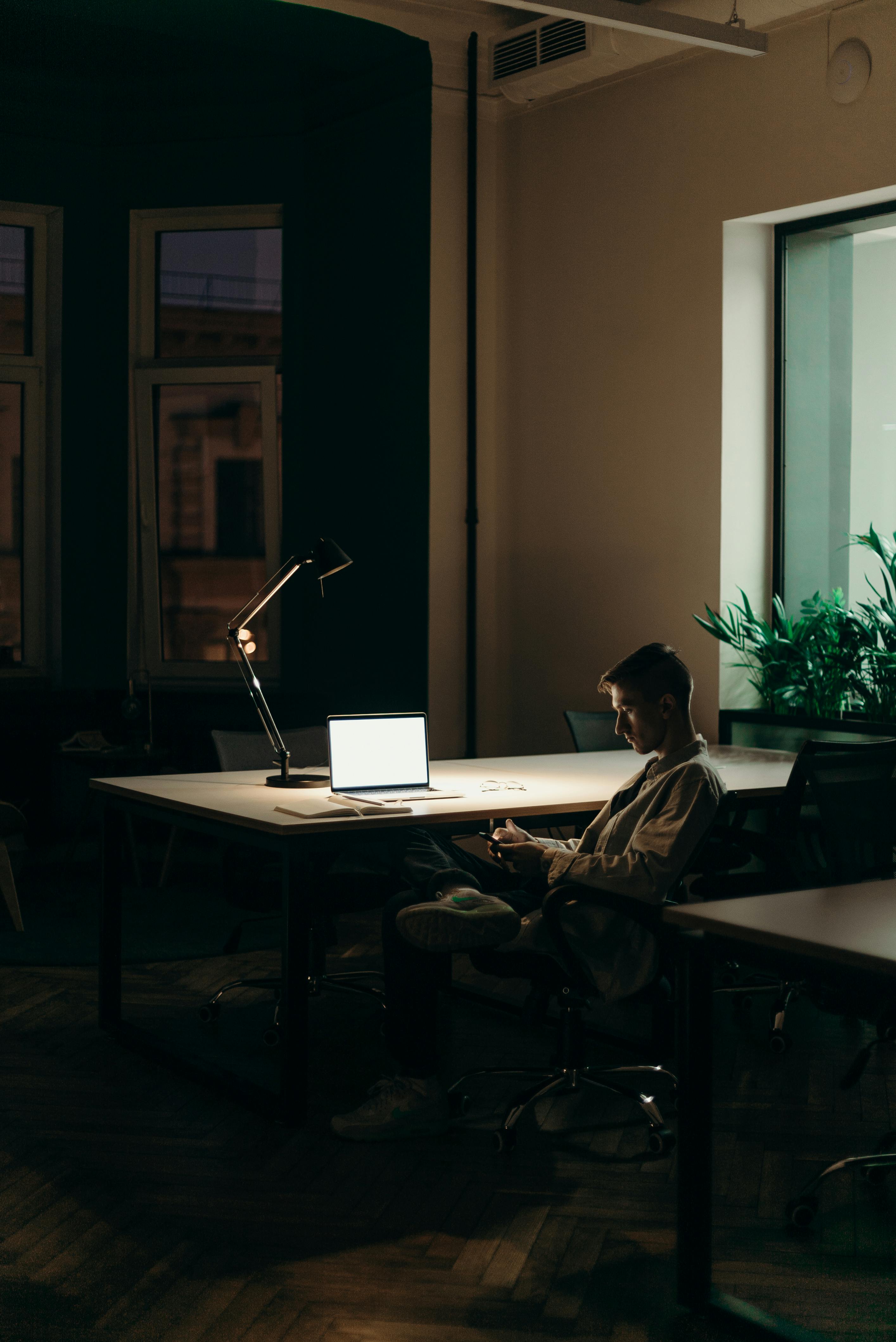 man in black and white plaid dress shirt sitting on chair in front of macbook