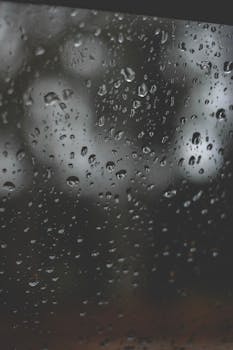 Raindrops on a window create a dreamy bokeh effect. Perfect for background or texture use.