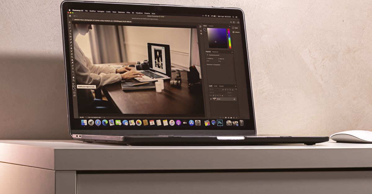 Laptop sobre un escritorio moderno mostrando una interfaz de software de edición de fotografías, con luz natural y ambiente de oficina.