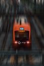 From above of red modern high speed train in motion on railway near platform on daytime