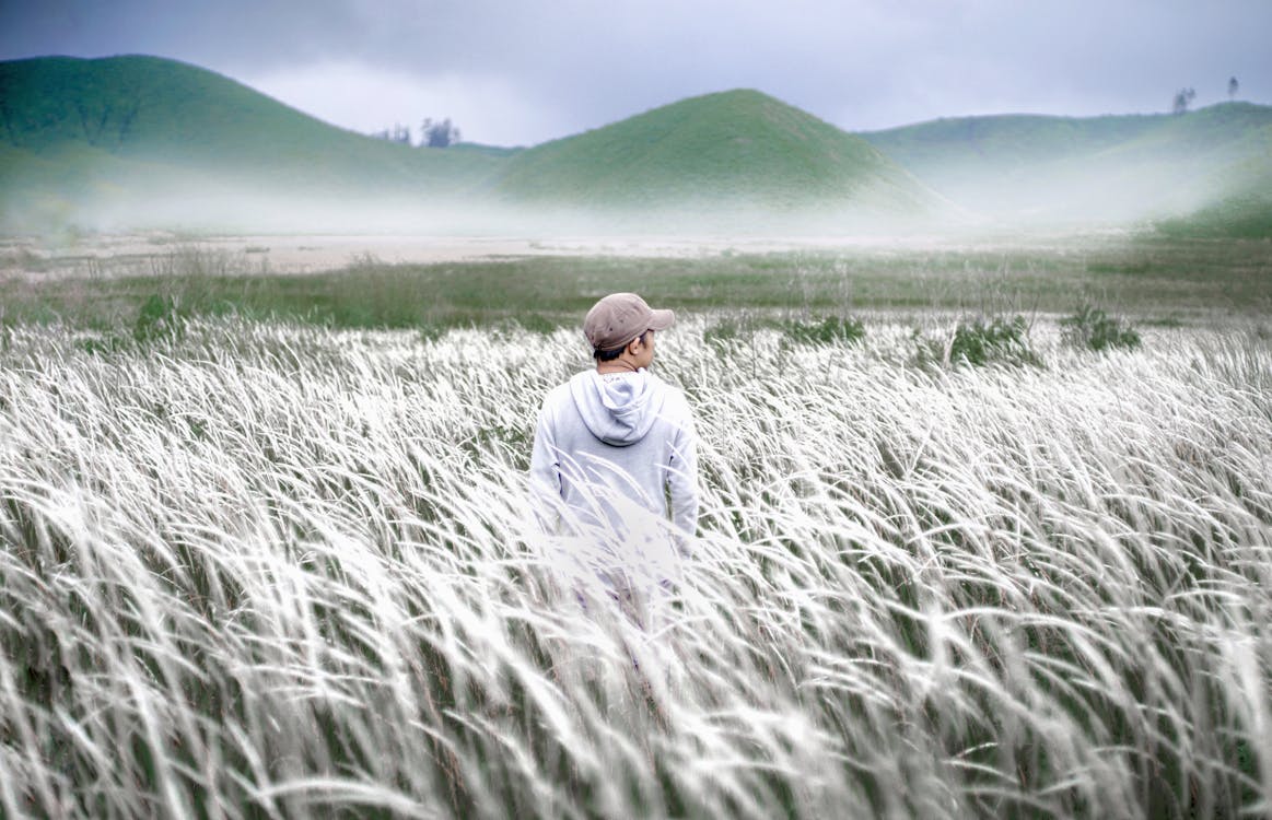 Man in White Hoodie Standing on Green Grass Field