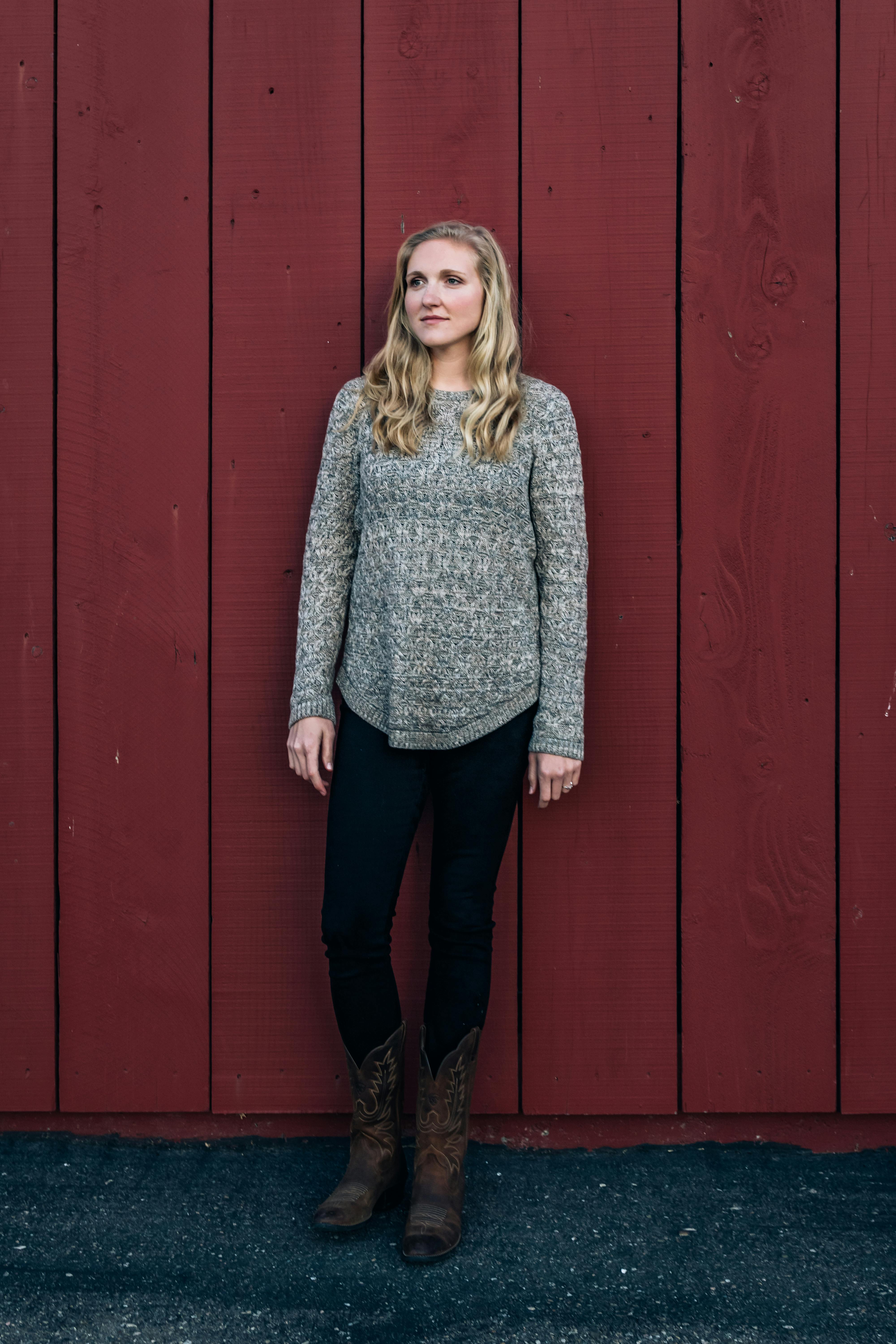 Portrait of a woman leaning against a rustic red wall in Santa Maria, California.