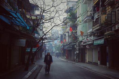 Man in Black Jacket Walking on Sidewalk