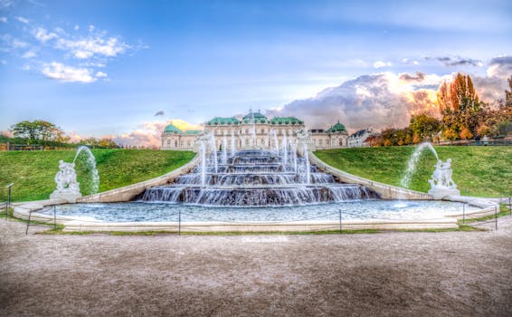 Captivating view of Belvedere Palace with lush gardens and dynamic fountains under a bright sky.