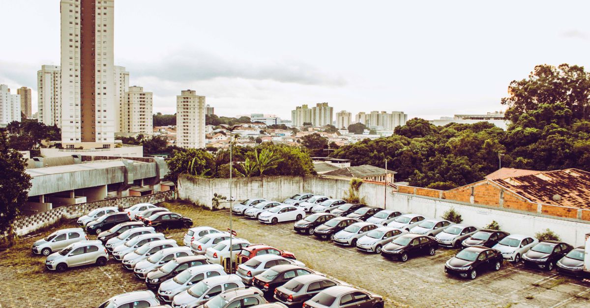 High angle view of cars parked in a city lot with skyline in the background.