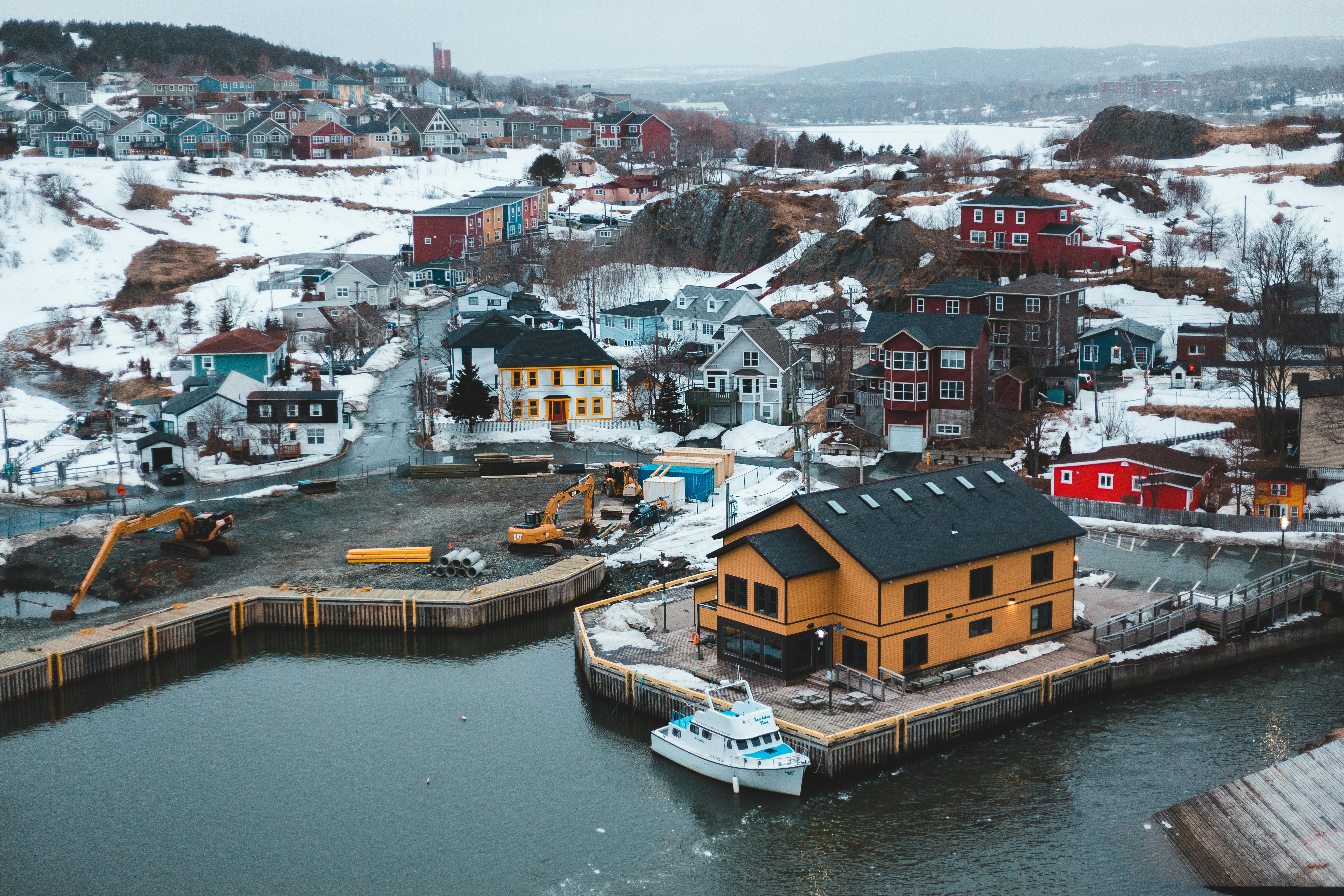 Snowy coastal town with colorful buildings and moored ship · Free Stock
