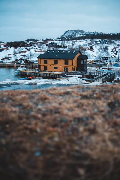 雪に覆われた山の近くの茶色の家