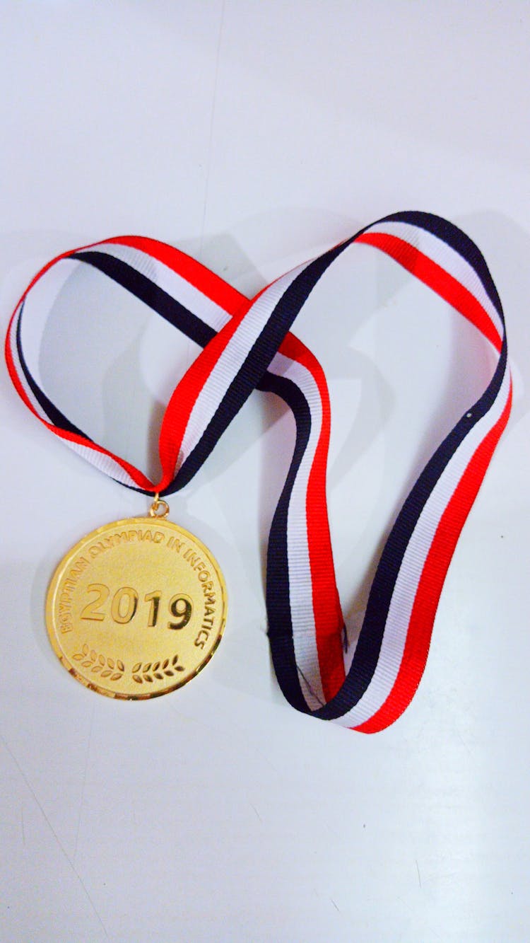 Gold Round Medal On White Surface