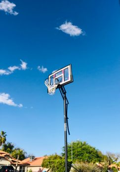 A basketball hoop stands tall against a clear blue sky on a sunny day.