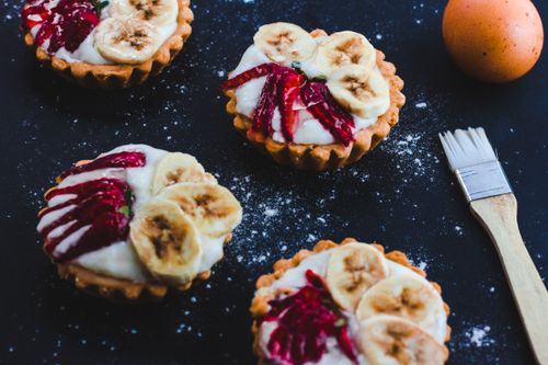 Free Close-up of homemade fruit tarts topped with bananas and berries, perfect for dessert. Stock Photo