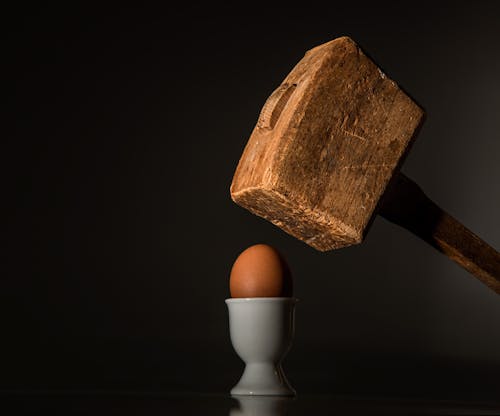 Коричневый деревянный молоток возле коричневого куриного яйца