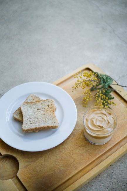 A cozy breakfast setup with toast and coffee on a wooden tray, styled with flowers.