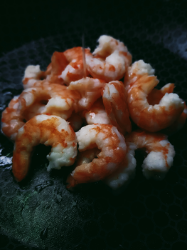 特写镜头聚焦于黑色表面上美味煮熟的虾，凸显了其丰富的质地