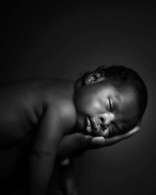 Grayscale Photo of Baby on Persons Hand