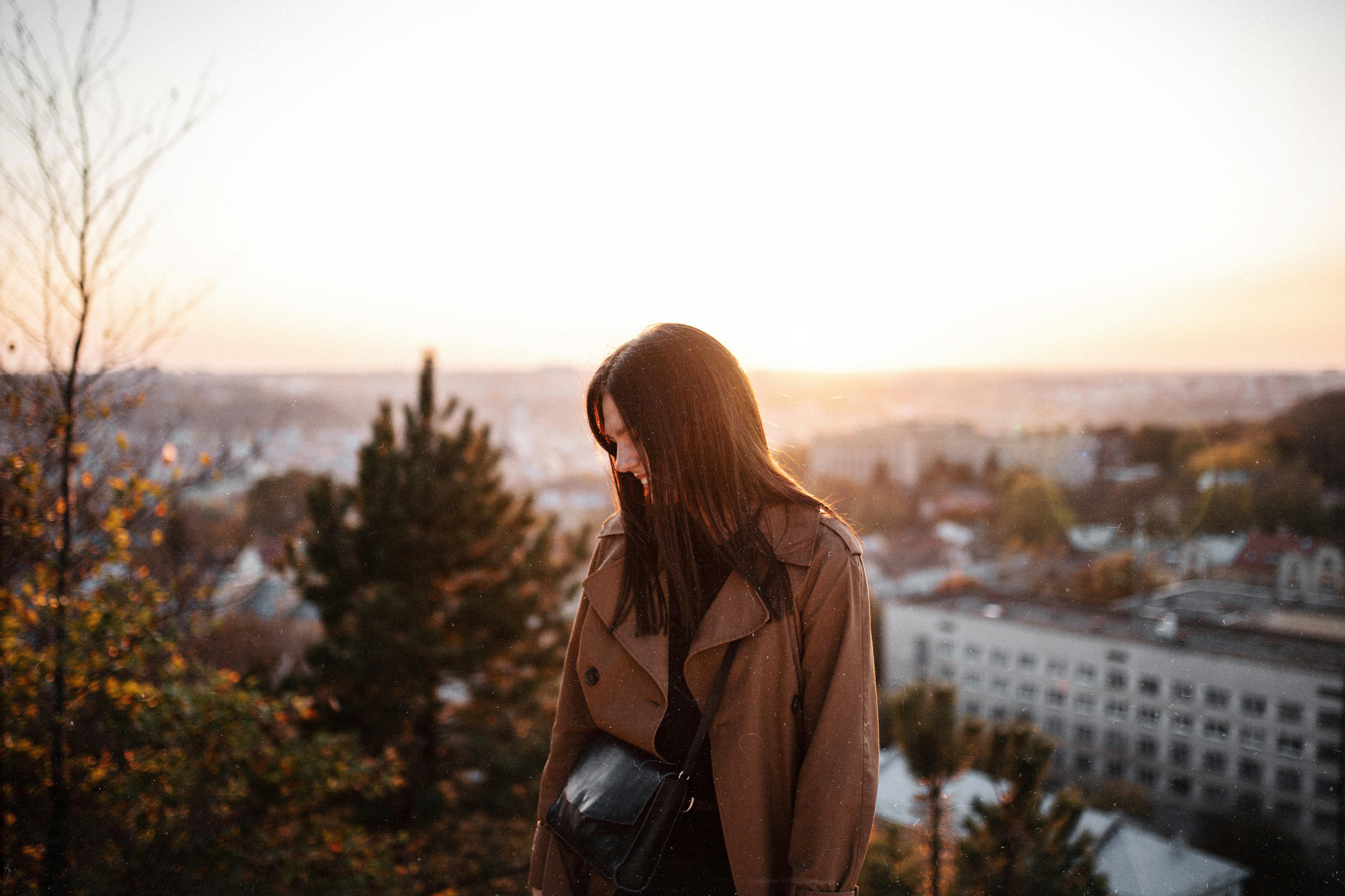 A woman enjoys a serene autumn sunset overlooking Vienna's cityscape.