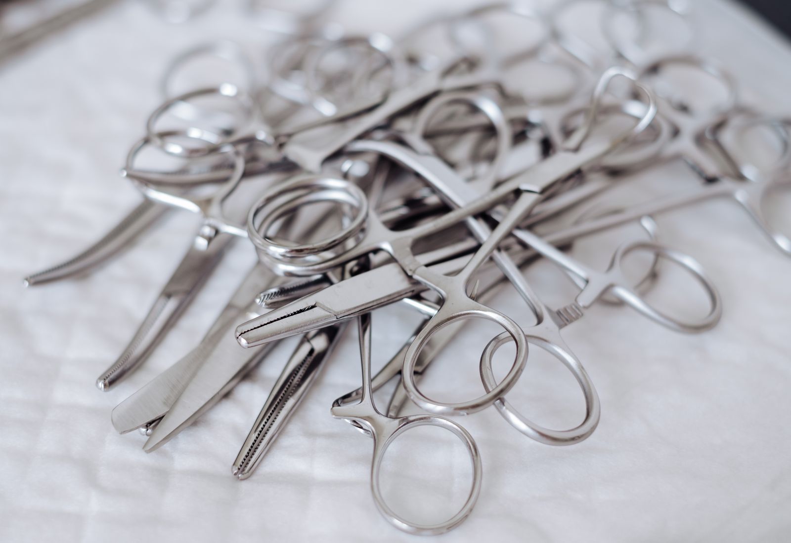 Macro composition of VOGUE stainless steel surgical instruments on a deep teal field