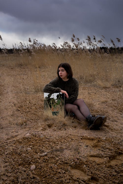Woman in Black Dress Sitting on Brown Grass Field