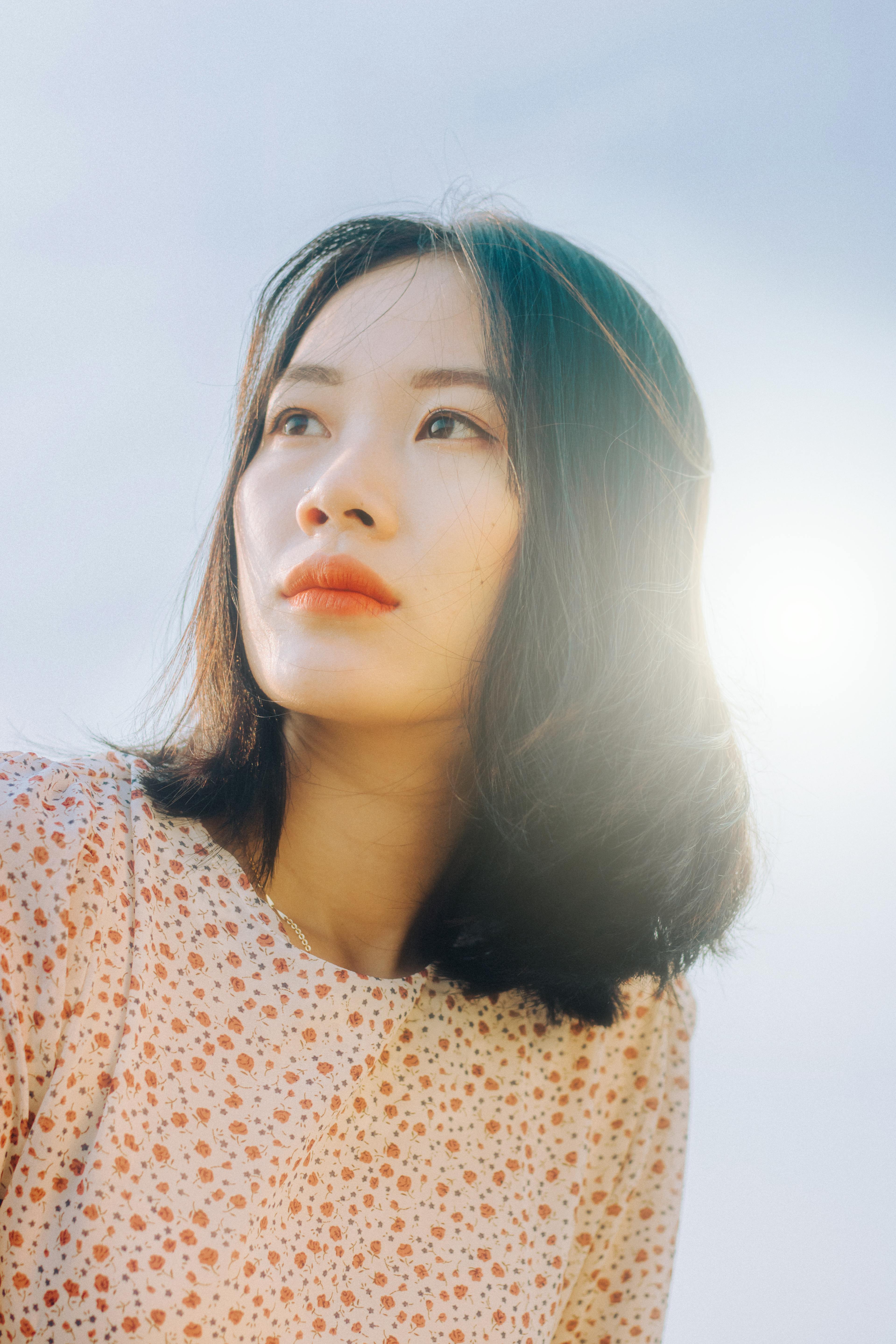 一位短发女子在明媚的阳光下仰头凝视，营造出梦幻般的氛围