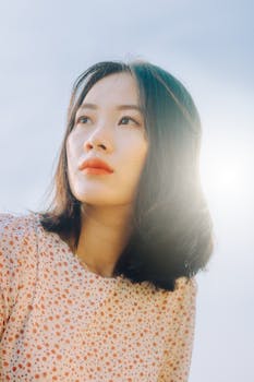 一位短发女子在明媚的阳光下仰头凝视，营造出梦幻般的氛围