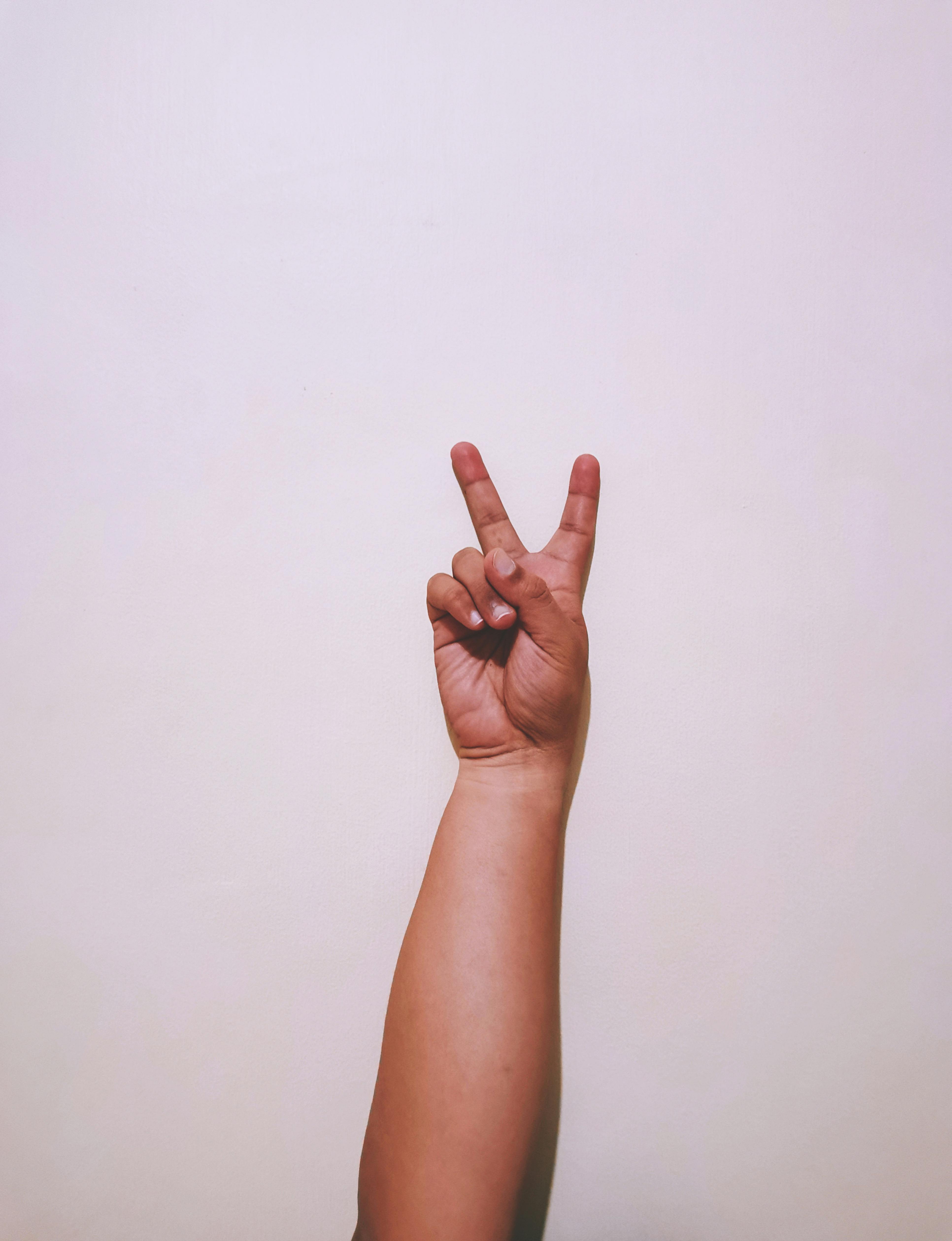 crop person showing v sign against white background