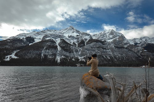 Free A Person Sitting on a Rock Boulder Taking Pictures Stock Photo
