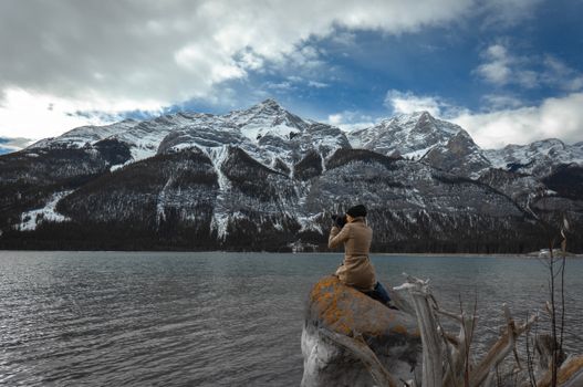 Photographer focuses on a stunning snow-covered mountain landscape at a serene lake in Canada.