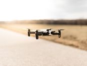 Soft focus of modern quadcopter flying above road out of city near forest