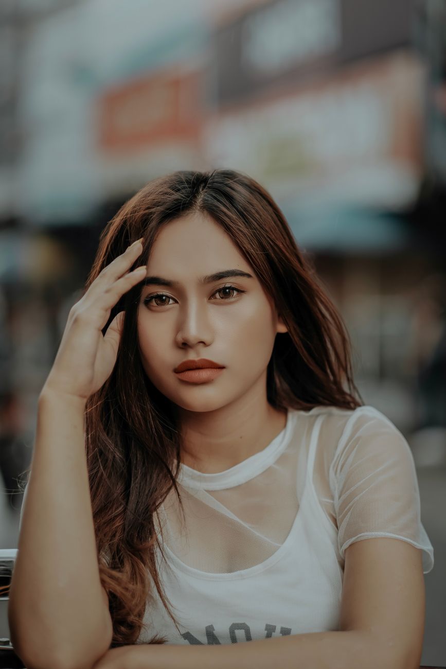 Chic portrait of a young Asian woman posing outdoors with a mesh top.