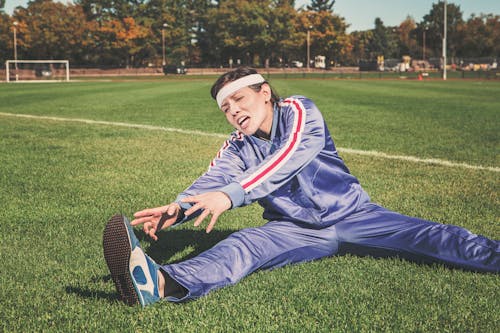 Woman Stretching on Grass Field