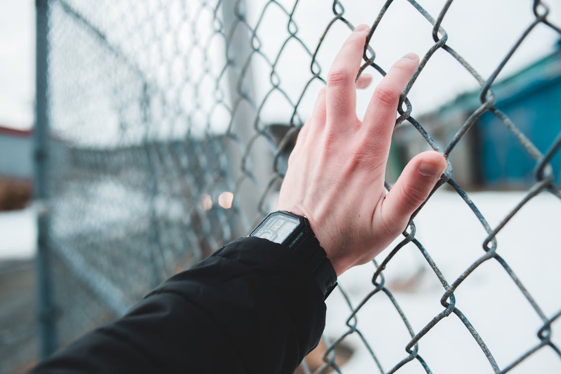 Free Person Wearing Black Watch Holding Gray Metal Fence Stock Photo