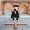 Man in Black Hoodie Sitting on Concrete Floor