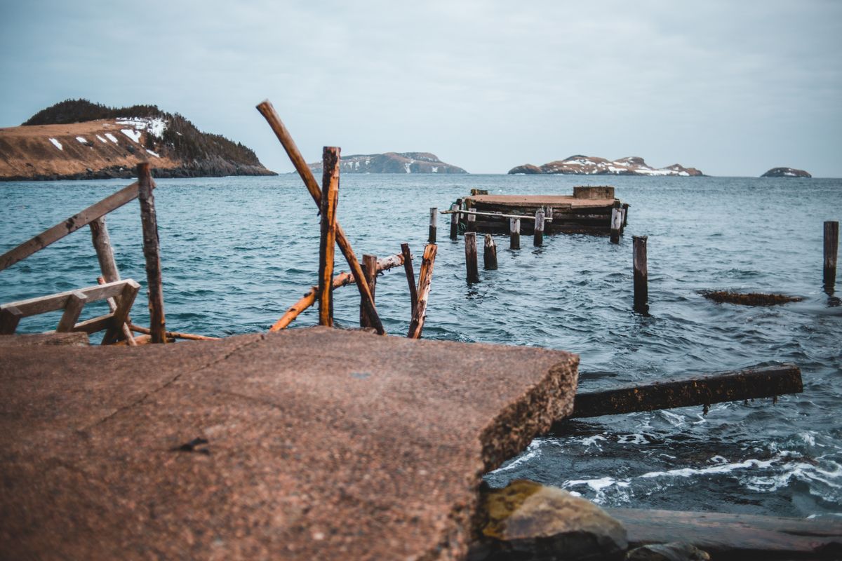 A broken dock overlooking the open ocean with distant islands under a cloudy sky near Nagasaki