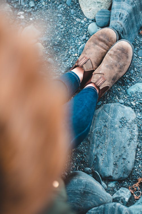 Free Person in Brown Suede Shoes Standing on Rocky Shore Stock Photo