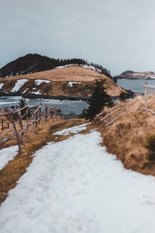 Brown Grass Field with Snow Near Body of Water