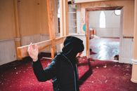 Man in Black Hoodie Leaning on Wooden Cross