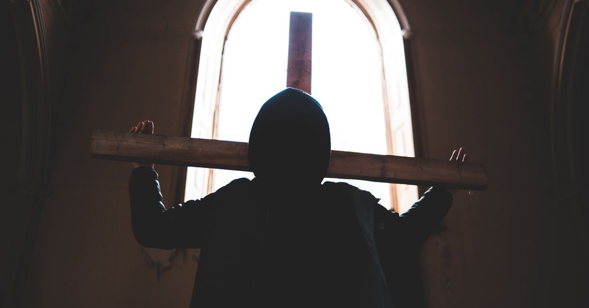 silhouette of a person standing in a demolished church with light shining through the roof