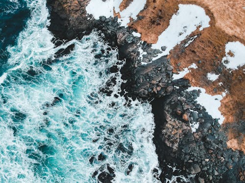 Aerial View of Ocean Waves Crashing on Rocky Shore