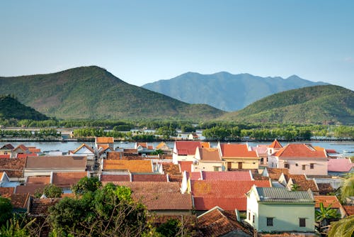 White and Brown Concrete Houses Near Green Mountain Under Blue Sky