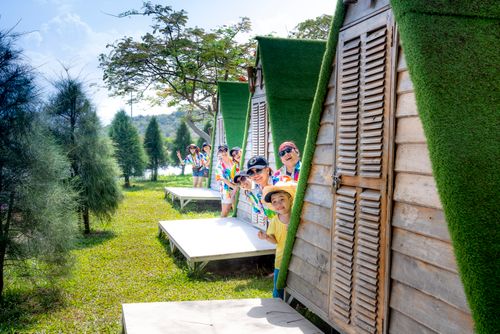 Free A cheerful family having fun outside colorful cabins in a sunny park setting. Stock Photo