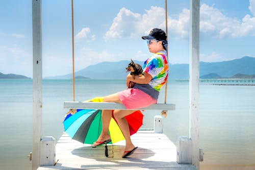 Free Woman Sitting on Wooden Swing Holding a Black Dog Stock Photo