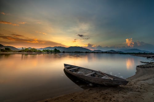 White and Brown Rowboat on Shore During Sunset