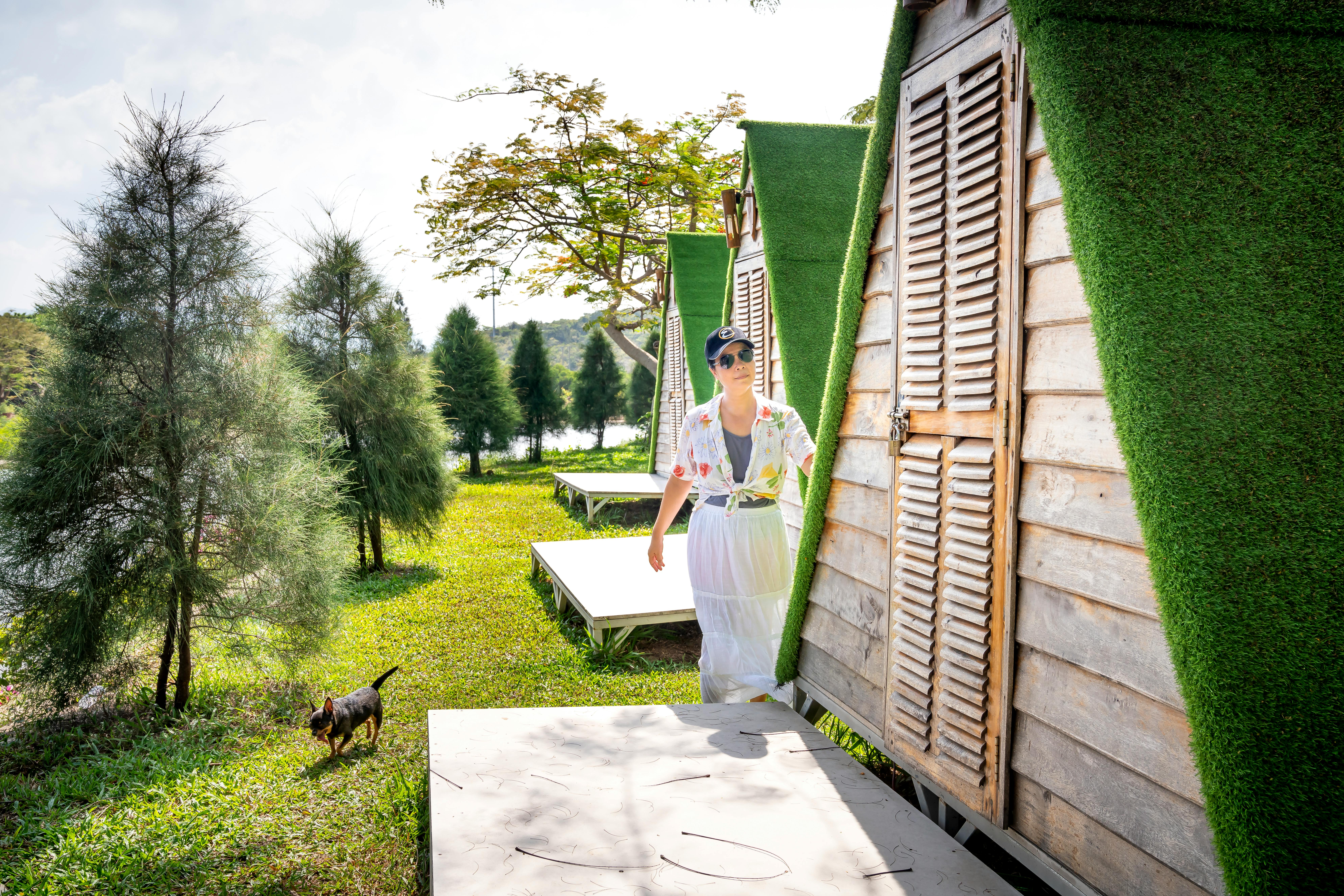 Woman with dog standing near porch of house in countryside