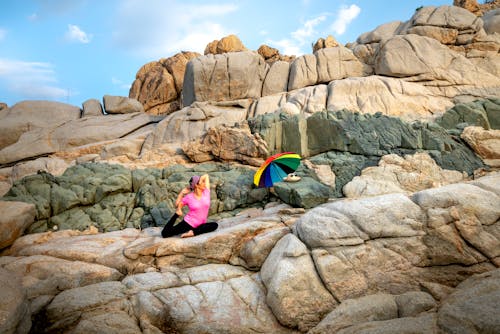Free Woman in Pink Shirt Sitting on Rock Stock Photo