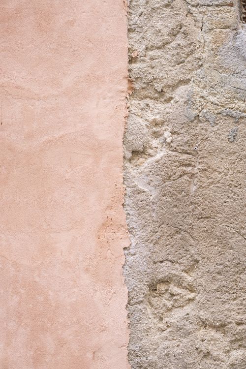Free Close-up of a rough stucco wall with contrasting pastel pink and beige textures. Stock Photo