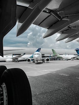 Several airplanes are parked on the airport tarmac under a cloudy sky, awaiting their next flights.