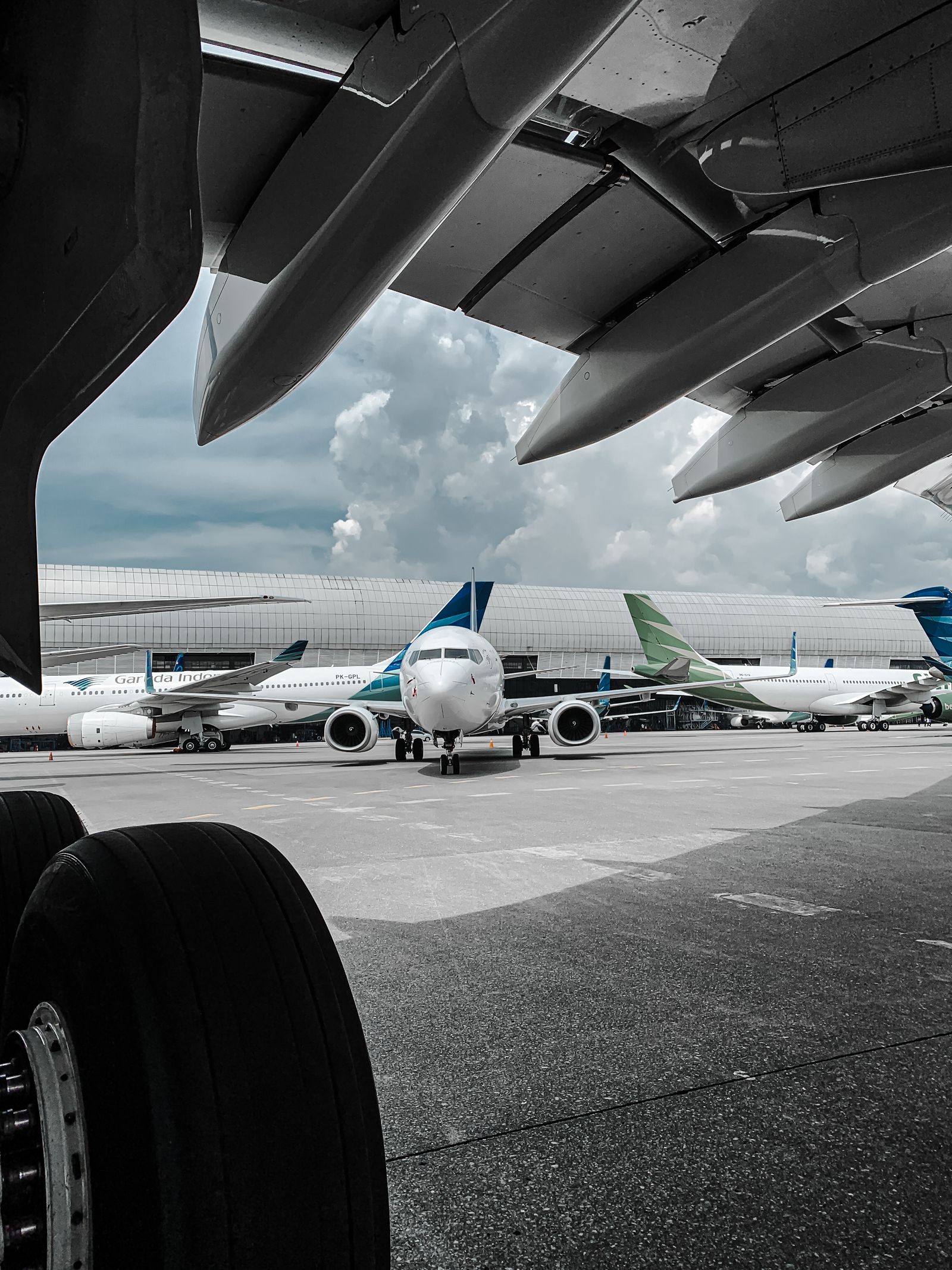 Several airplanes parked on the airport tarmac under a cloudy sky